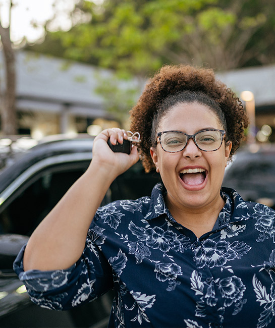 Woman excited about new car holding up keys with an open-mouth smile