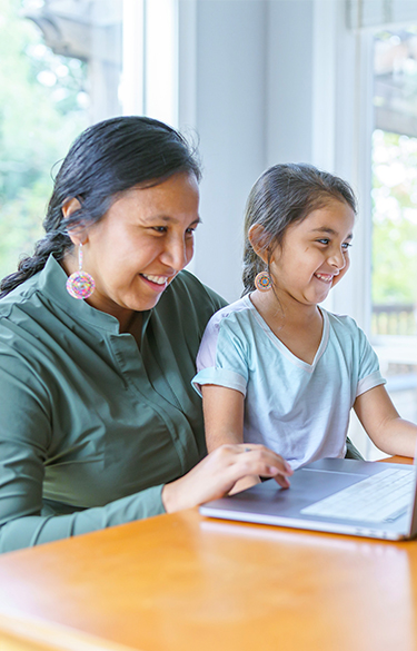 Mother with her child on her lap smiling looking at laptop