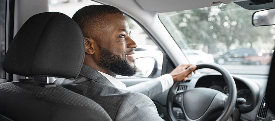 Young man smiling driving a car