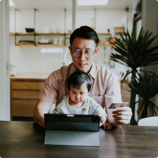 Father with child on lap while using a tablet