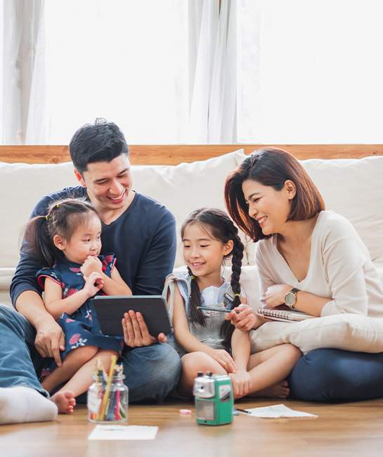 Family of four sitting on their living room floor with art supplies and a tablet