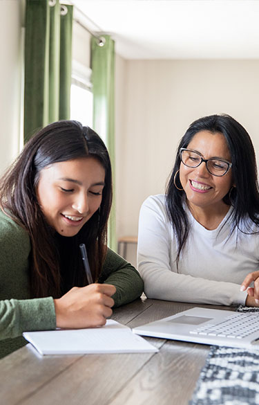 Mother and Daughter Using Laptop and Taking Notes 