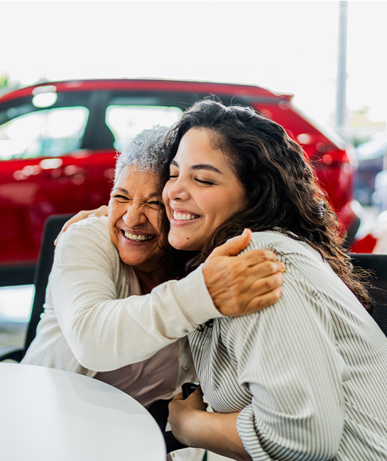 Mother and daughter hugging buying a new car