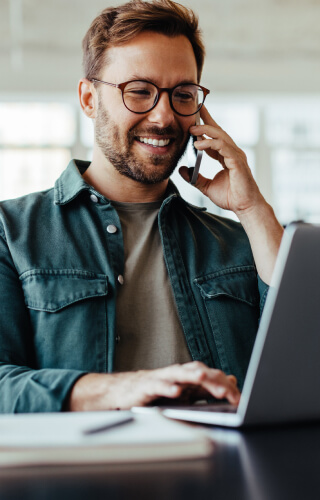 man using phone while on laptop 