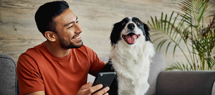 Man sitting with dog and holding phone
