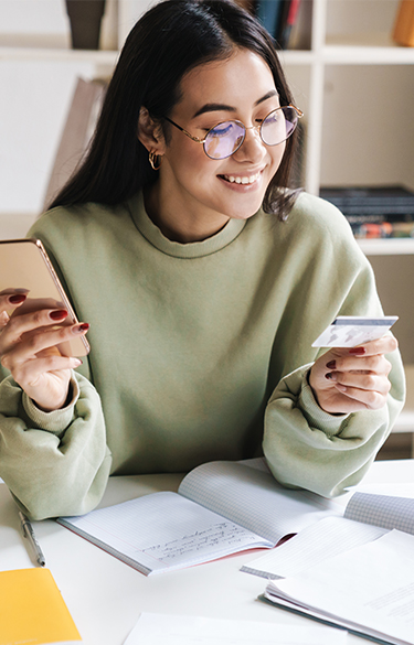 Young woman with glasses looking at card while holding a cell phone