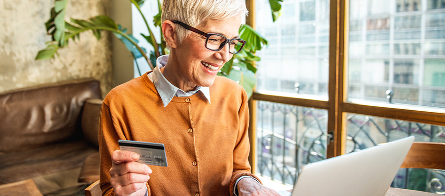 Woman smiling at her laptop holding a credit card