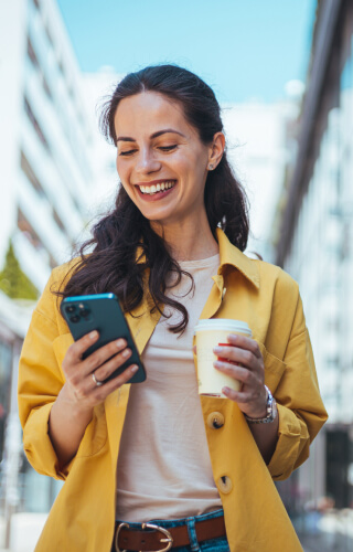 Young woman walking with coffee and mobile phone 