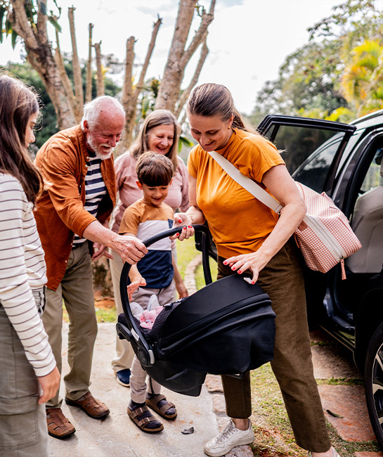 Older couple welcoming their family outside their home by a car