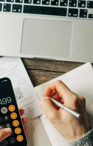 Person using mobile phone for calculator at desk