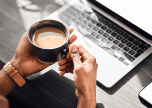 Person with coffee at computer desk