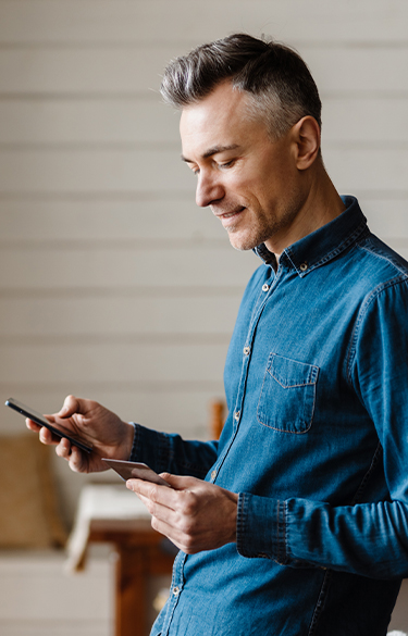 Man holding phone and credit card leaning against counter