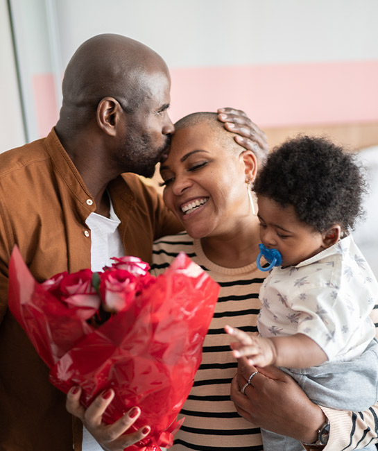 Couple with baby holding roses in their home