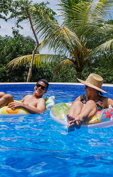 Middle aged couple floating in a pool on vacation