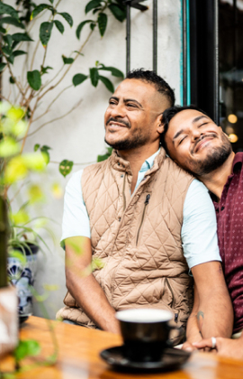 Same-sex couple smiling at coffee shop