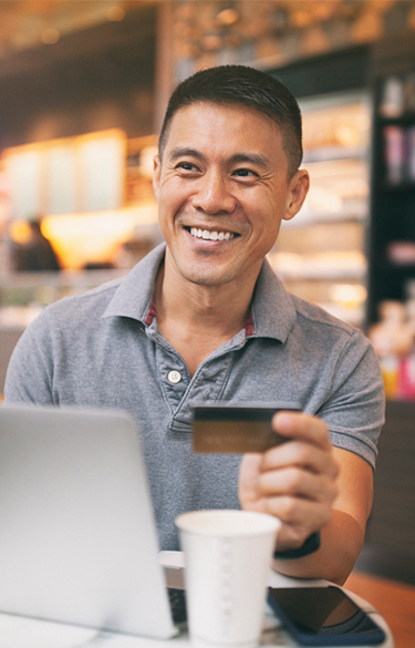 Man using credit card on laptop in a coffee shop