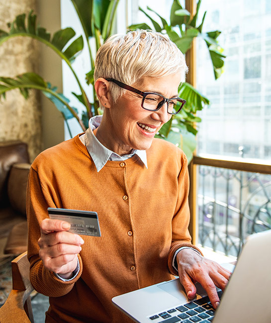 Woman smiling at her laptop holding a credit card