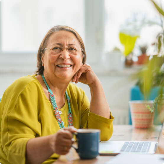 Mature woman smiling and looking at camera while at desk with coffee