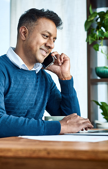 Man using a computer talking on his phone