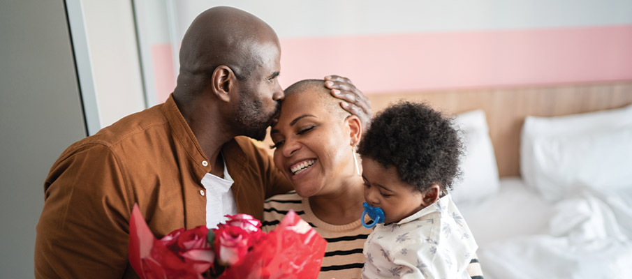 Couple with baby holding roses in their home