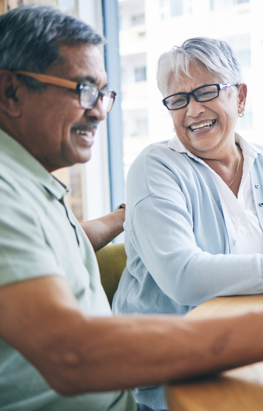 older couple smiling at each other siting at a table