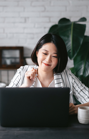 Young asian woman smiling at her computer 